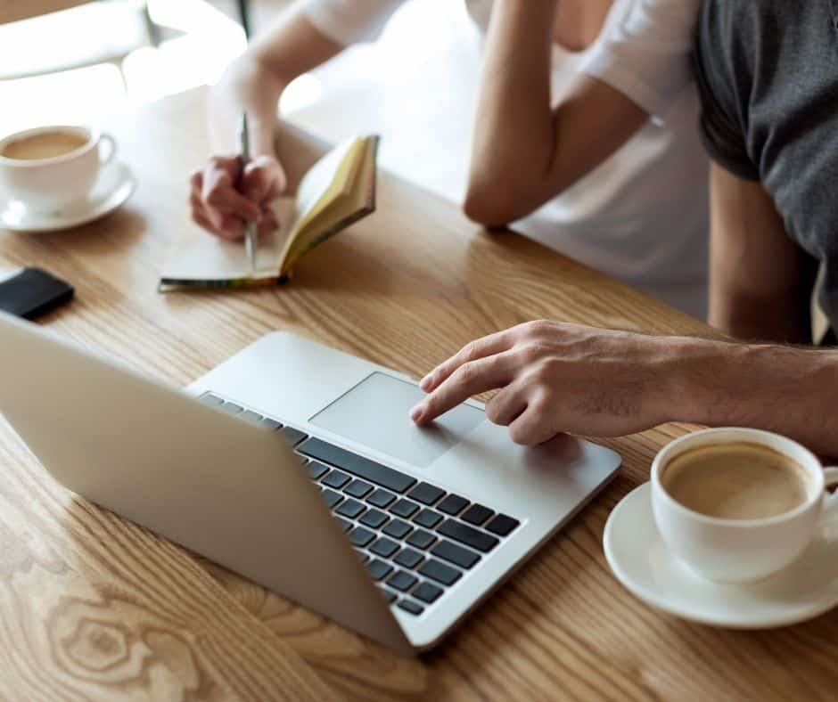 couple looking at laptop working on their budget over coffee